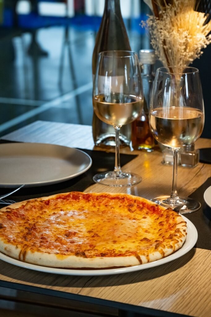 Pizza cuite au four et verres de vin servis au club house ZE PADEL